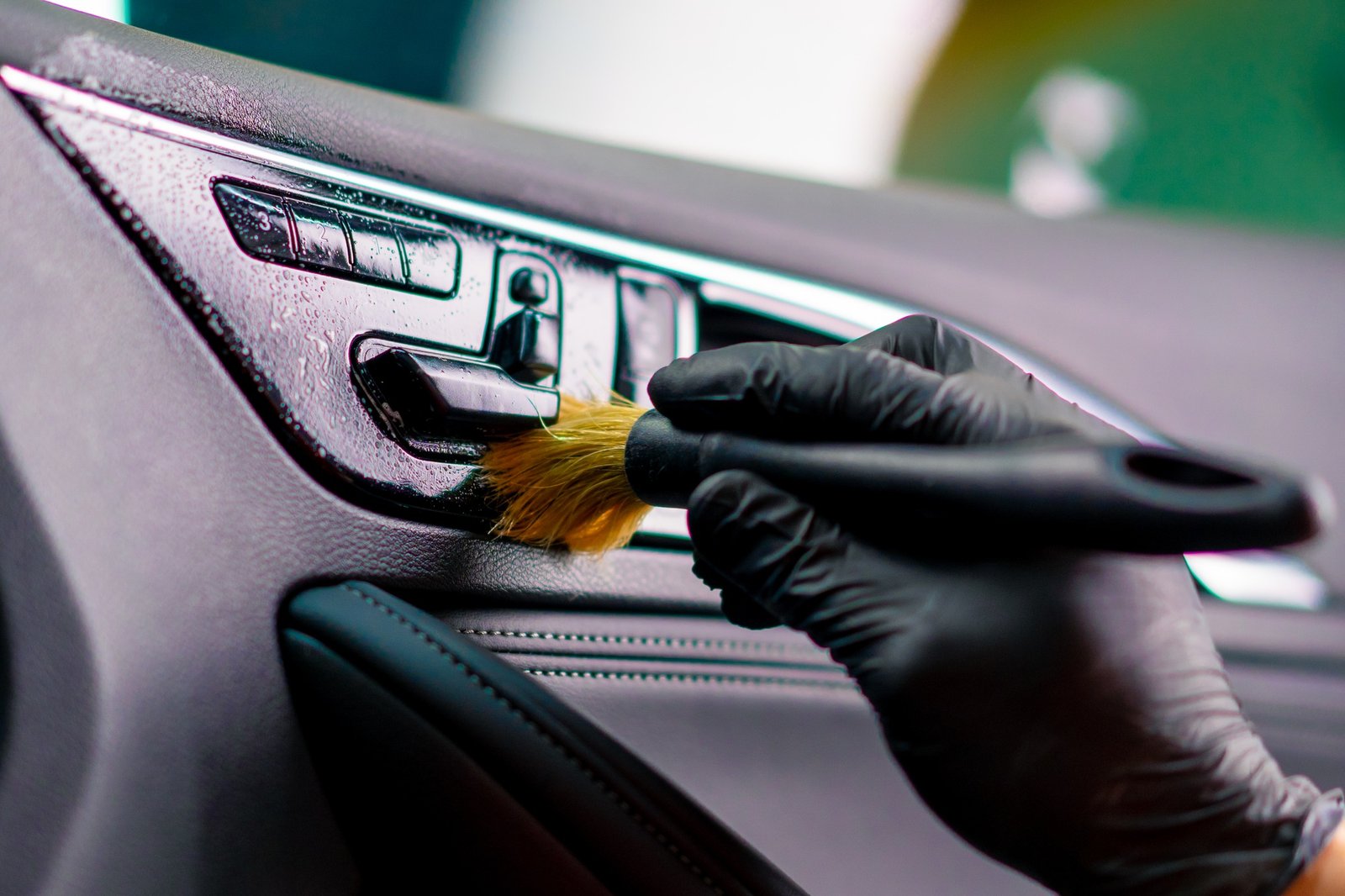 Car wash worker thoroughly cleaning the interior of a luxury car with a brush detailing close-up