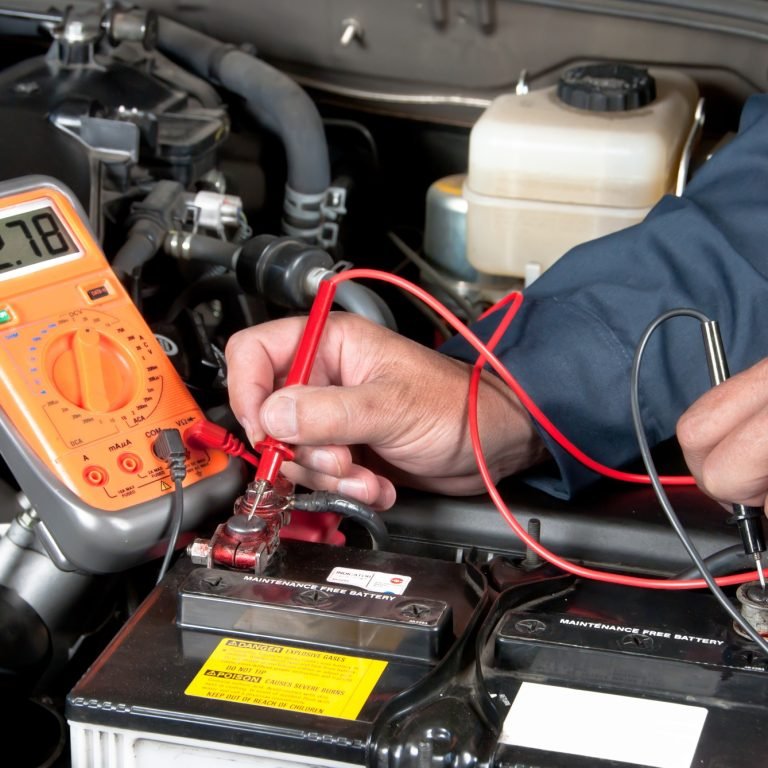 Auto mechanic checking car battery voltage